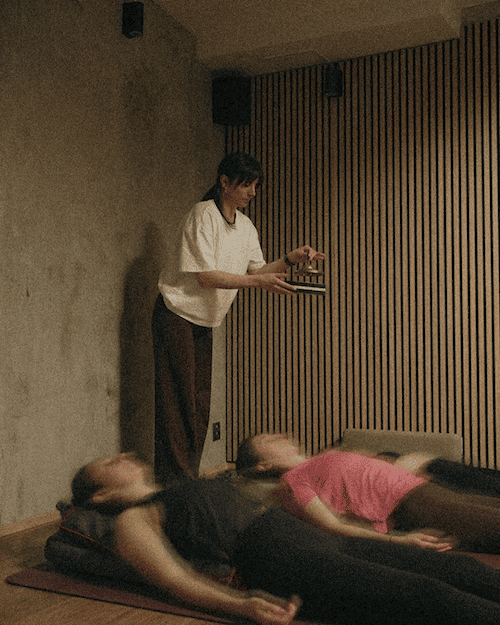 Lektorka s tibetskými zvonky během relaxace při józe ve studiu Yoga Movement.
