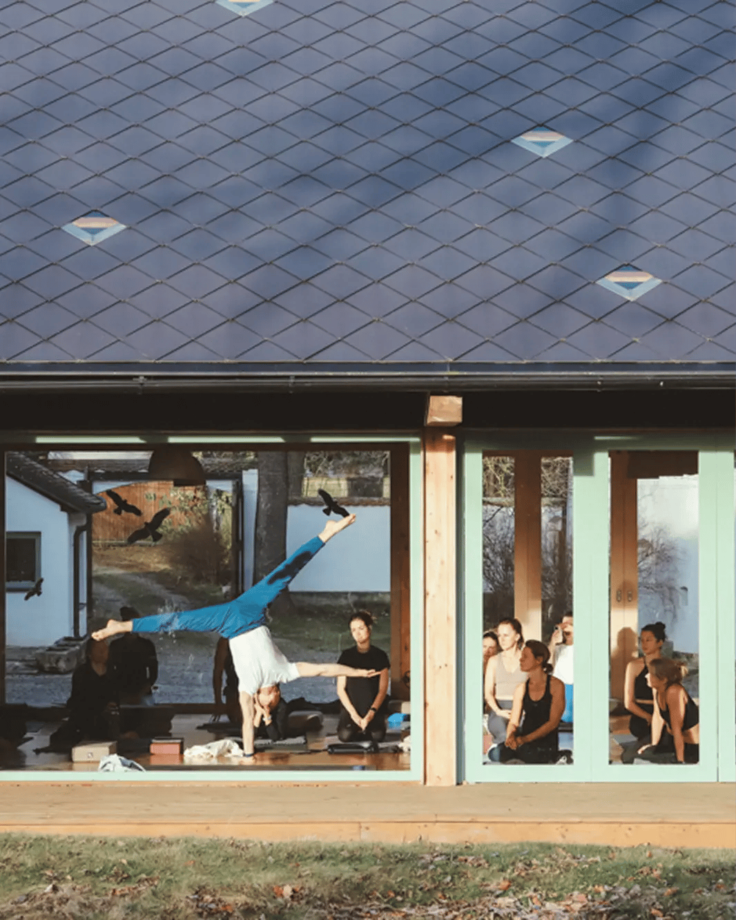 Pohled prosklenou stěnou na lekci jógy během retreatu Yoga Movement v usedlosti Manešovice.